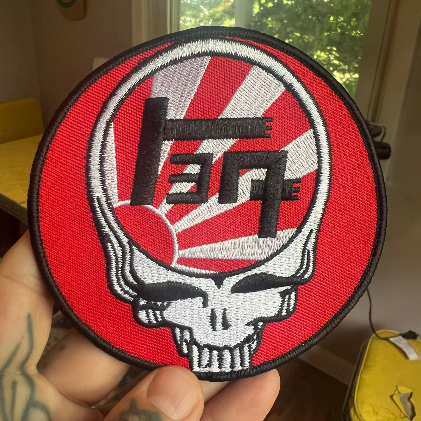 Embroidered Patch with Toyota TEQ symbol over the Japanese rising sun inside the Grateful Dead head skull design. Red and white circle on a white background